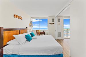 a bedroom with a large white bed with blue pillows at Stunning 1BR Ocean View Condo at Ilikai Marina in Honolulu