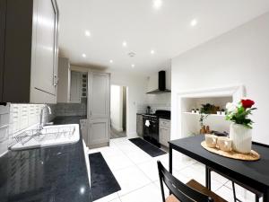 a kitchen with a table and a black counter top at Stylish 3 bed flat with Garden in London