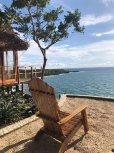 uma cadeira de madeira sentada na areia perto da água em Pamaduih - Suite Above the Sea em Cartagena das Índias