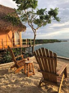 uma cadeira e um banco sentado na areia perto da água em Pamaduih - Suite Above the Sea em Cartagena das Índias