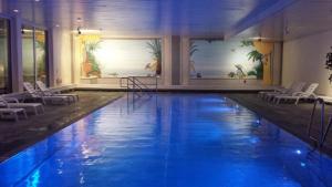 a large swimming pool with blue water in a building at Laax 1 12 Zi Whg mit Hallenbad, Aussen- Pool, Tennisplatz und Sauna in Laax