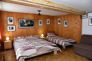 2 bedden in een slaapkamer met houten lambrisering bij Pri Matičku in Bohinj