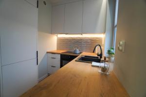 uma cozinha com armários brancos e um balcão de madeira em Apartament Manhattan em Płock