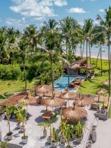 a resort with a pool and straw umbrellas and palm trees at Zai Patacho in Pôrto de Pedras