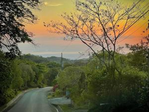 een lege weg met een zonsondergang op de achtergrond bij Chillout House in Monteverde Costa Rica +8 foto's