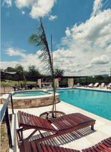 a swimming pool with a bench and a palm tree at Complejo Falda del Sauce in Villa General Belgrano
