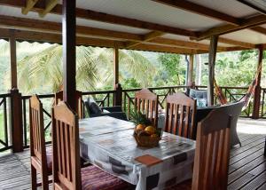 a dining table and chairs on a deck with a table and chairsktop at Domaine Karaibes in Deshaies