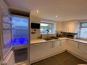 cocina con armarios blancos y nevera grande en Modern 4-bed Cottage Llanwrst Town Centre & Parking - Snowdonia! near Betws-y-Coed, en Llanrwst