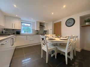 a kitchen with a table and chairs and a clock on the wall at Modern 4-bed Cottage Llanwrst Town Centre & Parking - Snowdonia! near Betws-y-Coed in Llanrwst