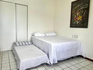1 dormitorio con 2 camas con sábanas blancas en Apto completo na orla da Pituba!, en Salvador