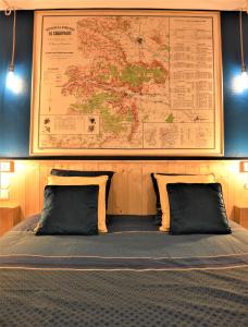 łóżko z dwoma poduszkami i mapą na ścianie w obiekcie Groom Épernay - Le Petit Tonnelier w Épernay