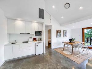 a kitchen with white cabinets and a wooden table at Two Doors in Broke