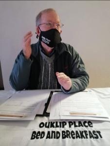 un hombre sentado en una mesa con una máscara en la cara en Ouklip Place Hotels en Roodepoort