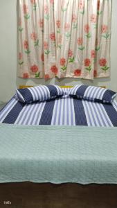 Bett mit zwei Kissen vor einem Fenster in der Unterkunft Inap Desa Morni in Kudat