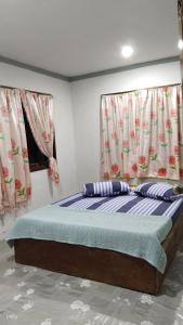 a bed in a room with two windows at Inap Desa Morni in Kudat