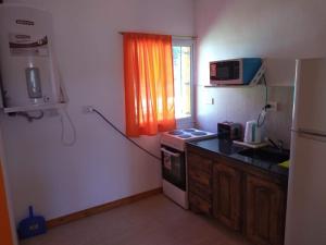 a small kitchen with a stove and a window at Cabañas El Doral in Potrero de los Funes
