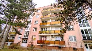 een roze appartementencomplex met balkons en bomen bij Panoráma Apartman in Veszprém