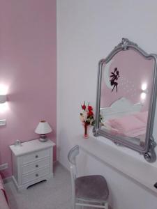 1 dormitorio con espejo, silla y tocador en La vie en rose, en Mola di Bari