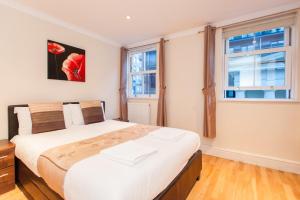ein Schlafzimmer mit einem großen Bett und zwei Fenstern in der Unterkunft London Serviced Apartments in London