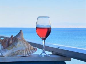 a glass of wine sitting on a ledge near the ocean at Niko's Apartment - Beautiful Sea View Apartment ! in Perea
