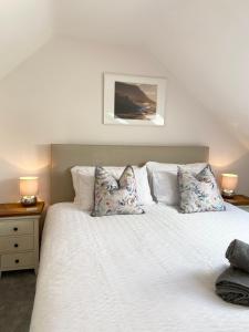 ein Schlafzimmer mit einem weißen Bett mit Kissen in der Unterkunft Modern 4-bed Cottage Llanwrst Town Centre & Parking - Snowdonia! near Betws-y-Coed in Llanrwst + 30 Fotos