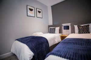 a bedroom with two beds with blue and white sheets at Isinmi Home - Close to MCR City in Manchester