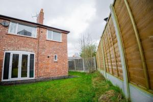 a brick house with a fence next to a yard at Isinmi Home - Close to MCR City in Manchester