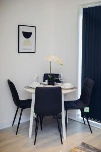 a dining room table with four chairs and a white table at Isinmi Home - Close to MCR City in Manchester