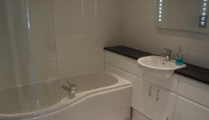 a white bathroom with a sink and a tub at The Lyn Valley Guest House in Lynmouth