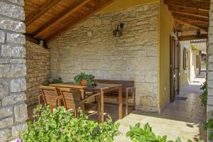 a stone walled patio with a wooden table and chairs at Alena in Debeljuhi (Haus für 4 Personen) in Žminj