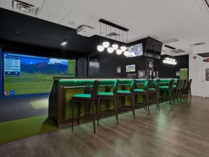 a bar with green chairs and a large screen at Best Western Plus Cairn Croft Hotel in Niagara Falls