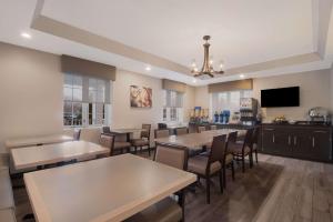 a dining room with tables and chairs and a flat screen tv at Best Western Colonel Butler Inn in Niagara on the Lake