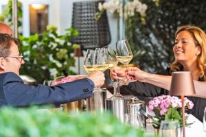 um homem e uma mulher sentados a uma mesa com copos de vinho em Parkhotel Engelsburg - 4 Sterne Superior em Recklinghausen