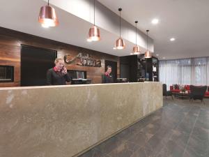 two men standing behind a counter in a lobby at Adina Apartment Hotel Sydney Airport in Sydney
