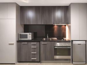 a kitchen with stainless steel appliances and a microwave at Adina Apartment Hotel Sydney Airport in Sydney