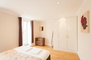 a white bedroom with a bed and a window at London Serviced Apartments in London