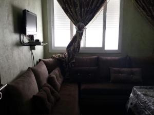 a couch in a living room with a window at Appartement D8 ARENA MARTIL in Martil