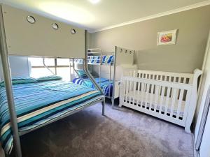 ein Schlafzimmer mit 2 Etagenbetten und einem Kinderbett in der Unterkunft Sandy Retreat on Royal Inverloch in Inverloch