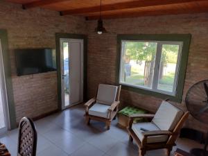 ein Wohnzimmer mit 2 Stühlen und einem TV in der Unterkunft Casa de campo Los Cardenales in Rafaela