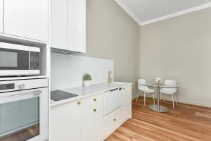 a white kitchen with a microwave and a table at Aloha Central Platinum Apartments in Mount Gambier