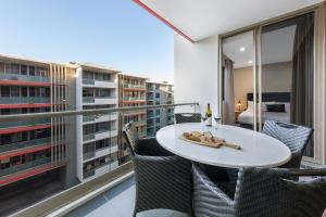 a balcony with a white table and chairs and a bedroom at Meriton Suites North Ryde in Sydney