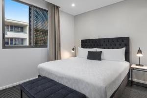 Un dormitorio con una cama grande y una ventana en Meriton Suites North Ryde en Sídney