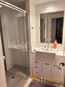 y baño con ducha, lavabo y espejo. en Relaxing Oasis in Bruce -1bd 1bth 1 carsp Apt, en Belconnen