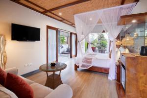 a living room with a bedroom with a bed and a tv at Ubud Nyuh Bali Resort & Spa in Ubud