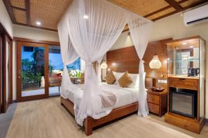 a bedroom with a canopy bed with white drapes at Ubud Nyuh Bali Resort & Spa - CHSE Certified in Ubud