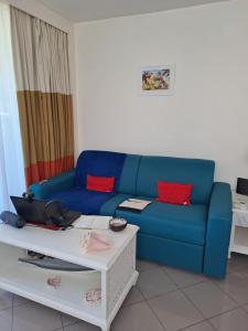 een woonkamer met een blauwe bank en een tafel bij F1 vue mer, accès plage, en centre-ville in Le Gosier