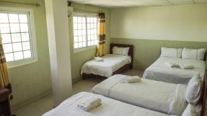 a room with three beds with white sheets and windows at Hotel Cristina in Bocas del Toro