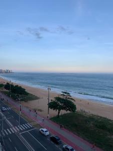 a view of the beach and the ocean with cars at A dois passos do mar… in Vila Velha