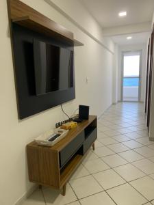 a living room with a television on a wall at A dois passos do mar… in Vila Velha