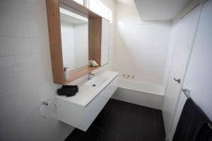 uma casa de banho branca com um lavatório e um espelho em MONREPOS em Point Lonsdale